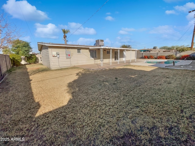 rear view of house featuring a fenced in pool, a patio, and a lawn