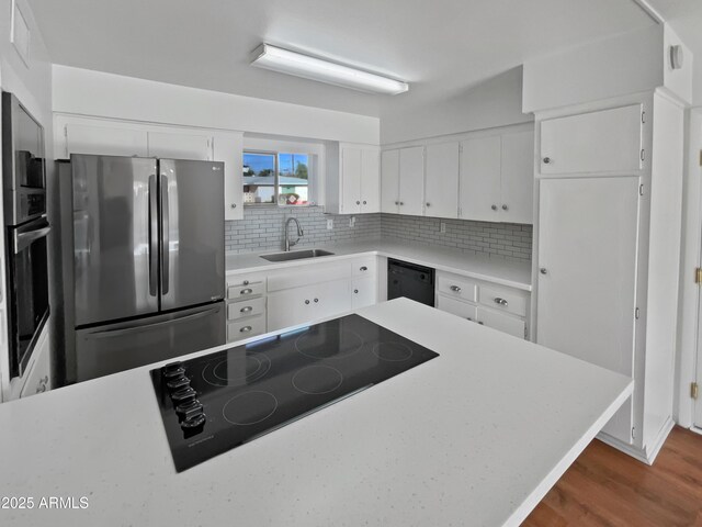 kitchen featuring decorative backsplash, sink, white cabinets, and black appliances