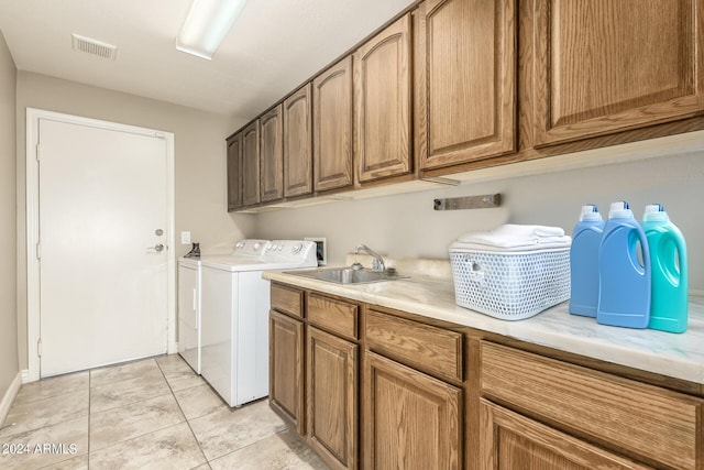 laundry room with cabinet space, visible vents, washing machine and dryer, a sink, and light tile patterned flooring