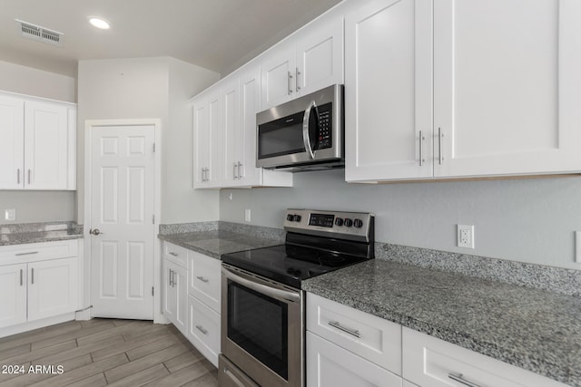 kitchen featuring white cabinets, appliances with stainless steel finishes, light hardwood / wood-style flooring, and stone countertops