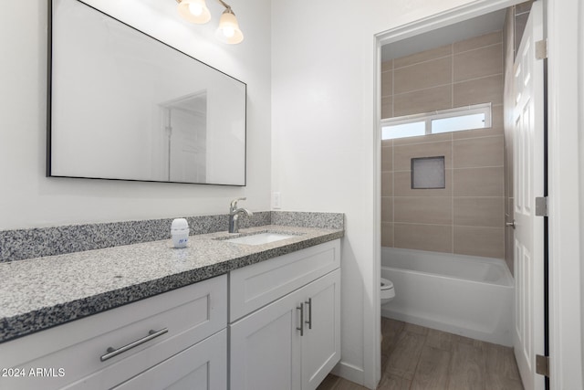 full bathroom featuring hardwood / wood-style floors, vanity, toilet, and tiled shower / bath combo