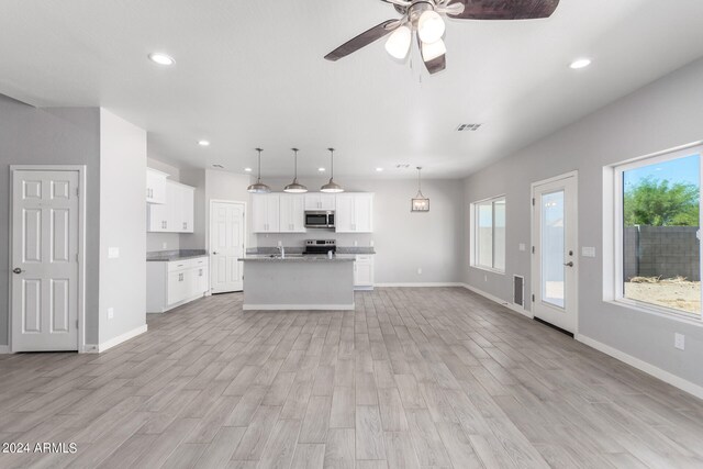 unfurnished living room featuring ceiling fan, light wood-type flooring, and sink