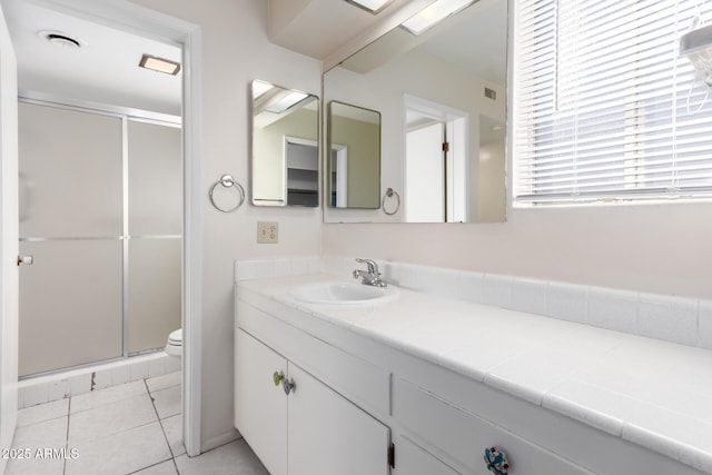 bathroom featuring vanity, toilet, a shower with shower door, and tile patterned flooring