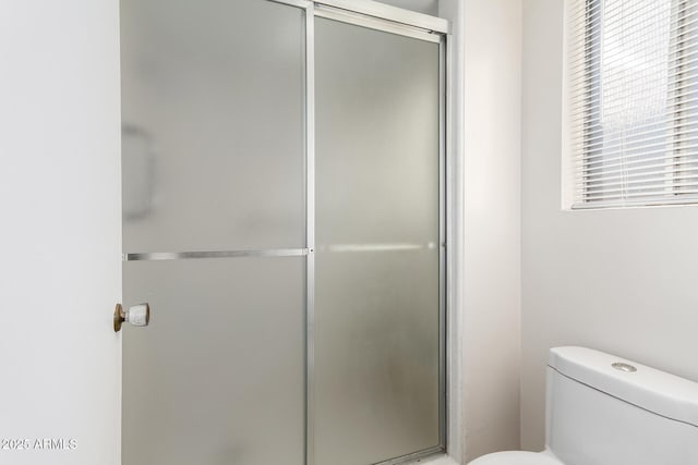 bathroom featuring toilet and a shower with shower door