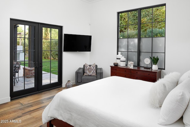 bedroom featuring french doors, multiple windows, access to outside, and light hardwood / wood-style flooring