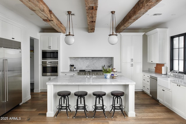 kitchen featuring beam ceiling, hanging light fixtures, white cabinetry, and built in appliances