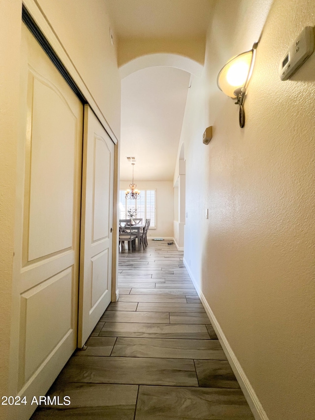 corridor with a notable chandelier and dark hardwood / wood-style flooring