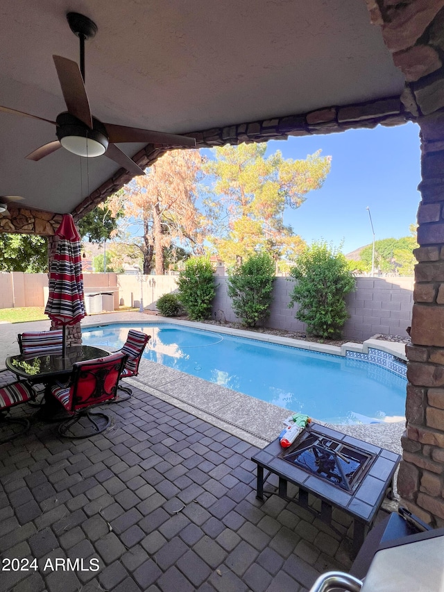 view of swimming pool with ceiling fan and a patio area