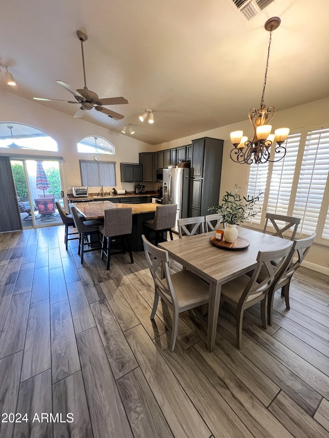 dining room featuring ceiling fan with notable chandelier, vaulted ceiling, and hardwood / wood-style flooring