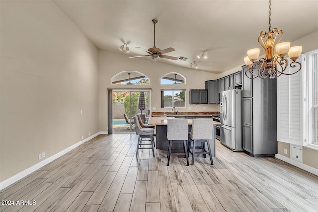 kitchen featuring a breakfast bar area, light wood-type flooring, stainless steel refrigerator with ice dispenser, vaulted ceiling, and sink