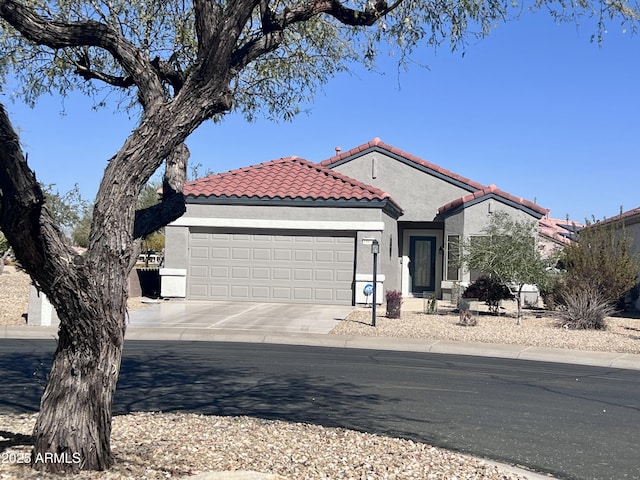 view of front of house with a garage, concrete driveway, a tile roof, and stucco siding