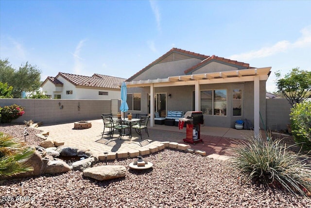 rear view of house with a patio area, a fenced backyard, a fire pit, and stucco siding