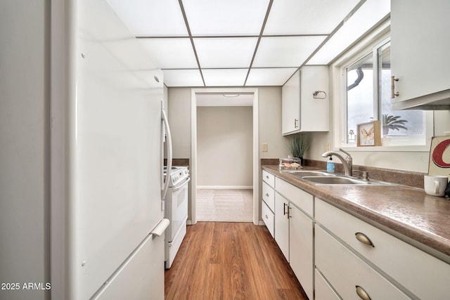 kitchen with white cabinetry, sink, and white appliances