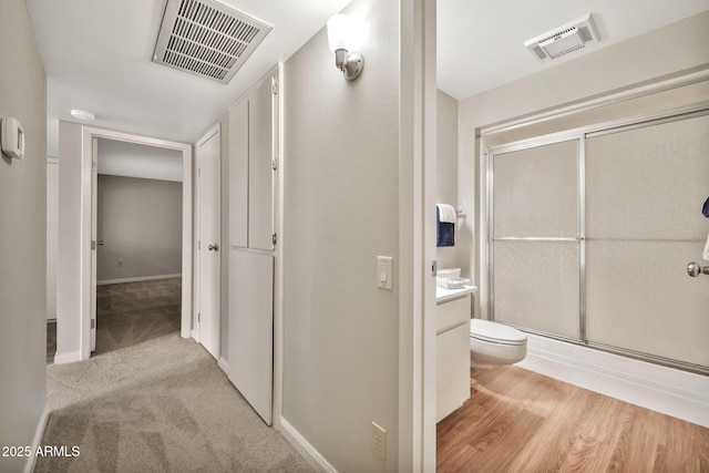 bathroom featuring toilet, vanity, and a shower with shower door