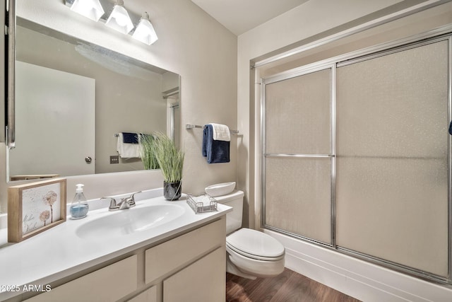 bathroom featuring hardwood / wood-style flooring, vanity, a shower with shower door, and toilet