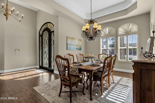 dining room with a notable chandelier, dark hardwood / wood-style flooring, and a tray ceiling