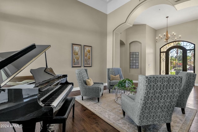 sitting room featuring hardwood / wood-style flooring, a towering ceiling, and an inviting chandelier