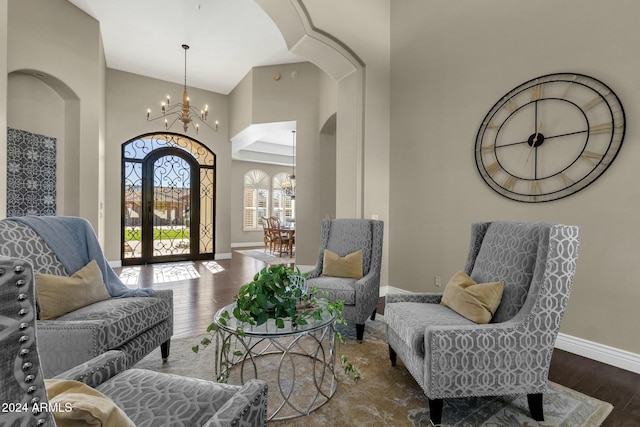 living area featuring a chandelier, high vaulted ceiling, and dark wood-type flooring