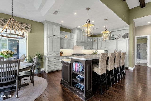 kitchen with a center island with sink, dark hardwood / wood-style floors, pendant lighting, and white cabinetry