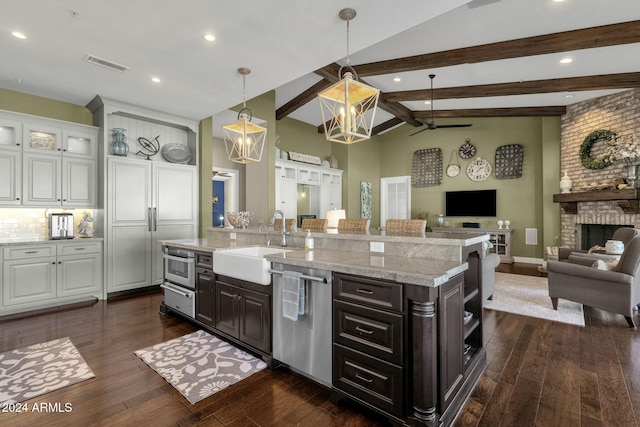 kitchen with dishwasher, white cabinets, sink, a brick fireplace, and dark hardwood / wood-style flooring