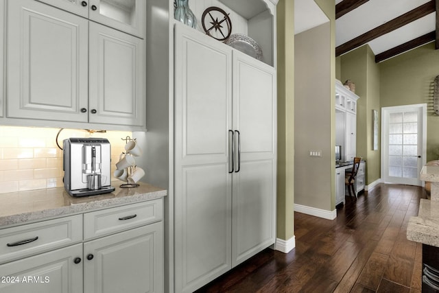 interior space featuring white cabinetry, dark wood-type flooring, tasteful backsplash, light stone counters, and beamed ceiling