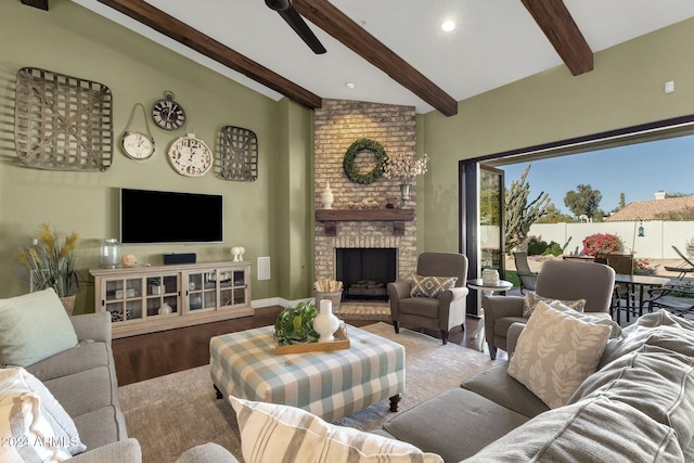 living room featuring vaulted ceiling with beams, ceiling fan, a fireplace, and light wood-type flooring