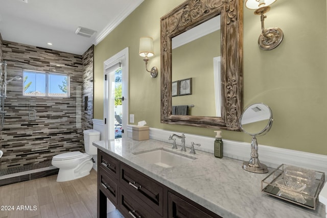 bathroom featuring vanity, crown molding, tiled shower, hardwood / wood-style floors, and toilet