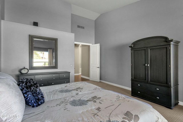 carpeted bedroom with high vaulted ceiling