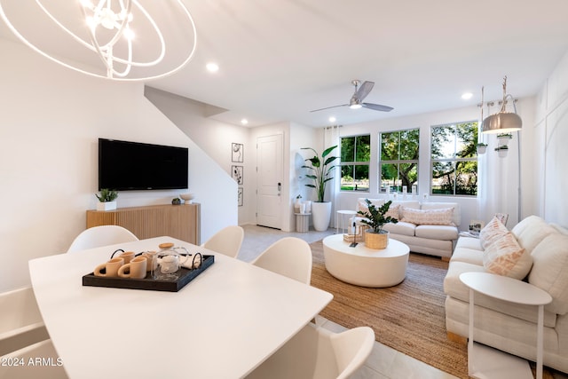 tiled living room featuring ceiling fan with notable chandelier