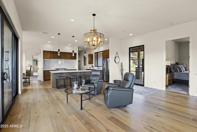 living room featuring light wood-type flooring, visible vents, a notable chandelier, and recessed lighting