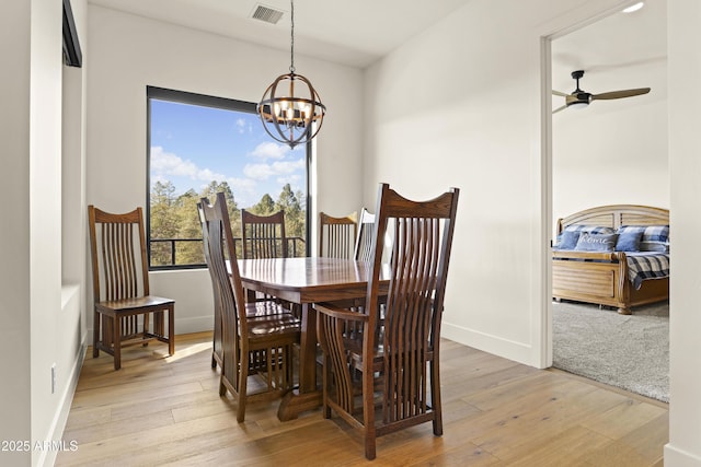 dining space featuring visible vents, light wood-style flooring, baseboards, and ceiling fan with notable chandelier