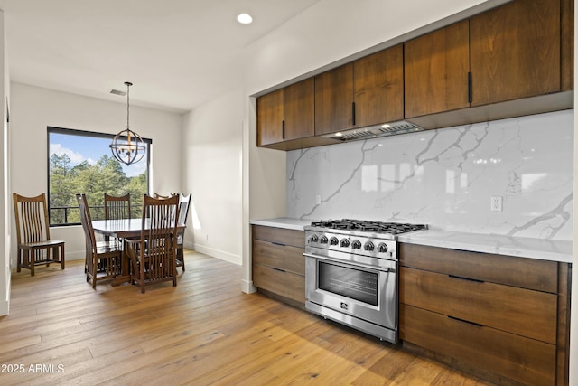 kitchen featuring tasteful backsplash, baseboards, light wood-style flooring, high end stove, and a chandelier