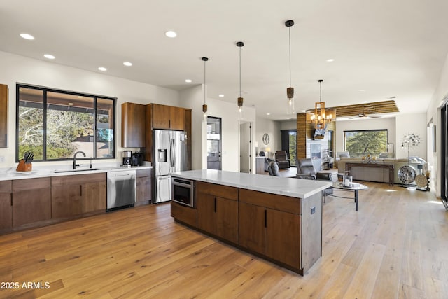 kitchen featuring a center island, stainless steel appliances, open floor plan, a sink, and modern cabinets