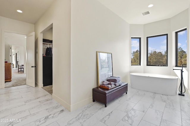 full bathroom with marble finish floor, a spacious closet, a freestanding bath, and recessed lighting