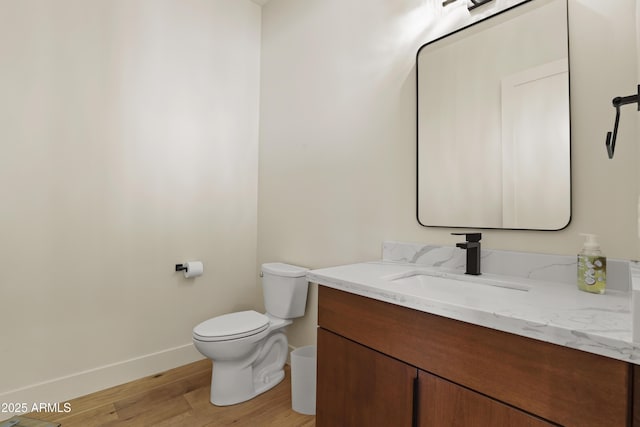 bathroom with toilet, baseboards, wood finished floors, and vanity