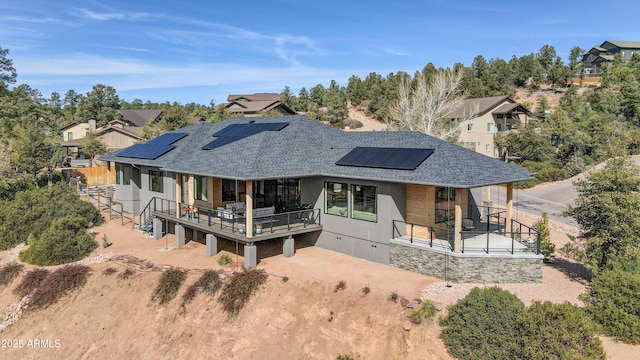 rear view of house with a shingled roof and roof mounted solar panels