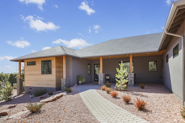 view of front of home with a patio, a shingled roof, and stucco siding