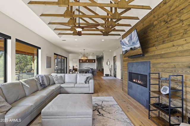 living area with light wood finished floors, visible vents, a glass covered fireplace, high vaulted ceiling, and recessed lighting