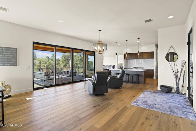 living area featuring a chandelier, light wood-type flooring, visible vents, and recessed lighting