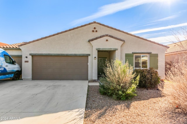 mediterranean / spanish house featuring an attached garage, driveway, a tile roof, and stucco siding