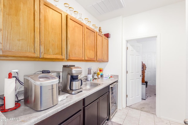 kitchen with light tile patterned flooring, beverage cooler, a sink, visible vents, and light countertops