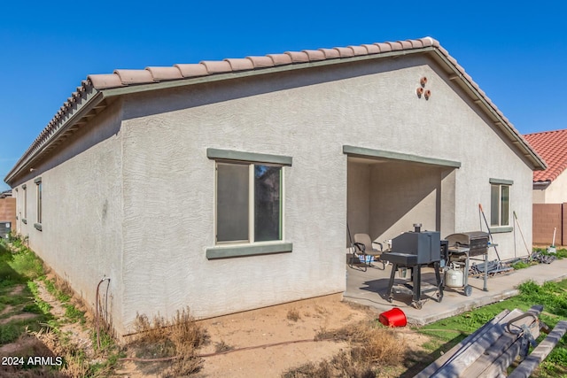 back of property featuring a patio area, a tiled roof, fence, and stucco siding