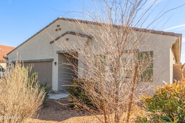 view of front facade featuring a tiled roof, an attached garage, and stucco siding