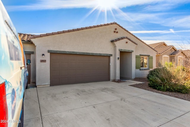 mediterranean / spanish-style house with an attached garage, driveway, a tiled roof, and stucco siding