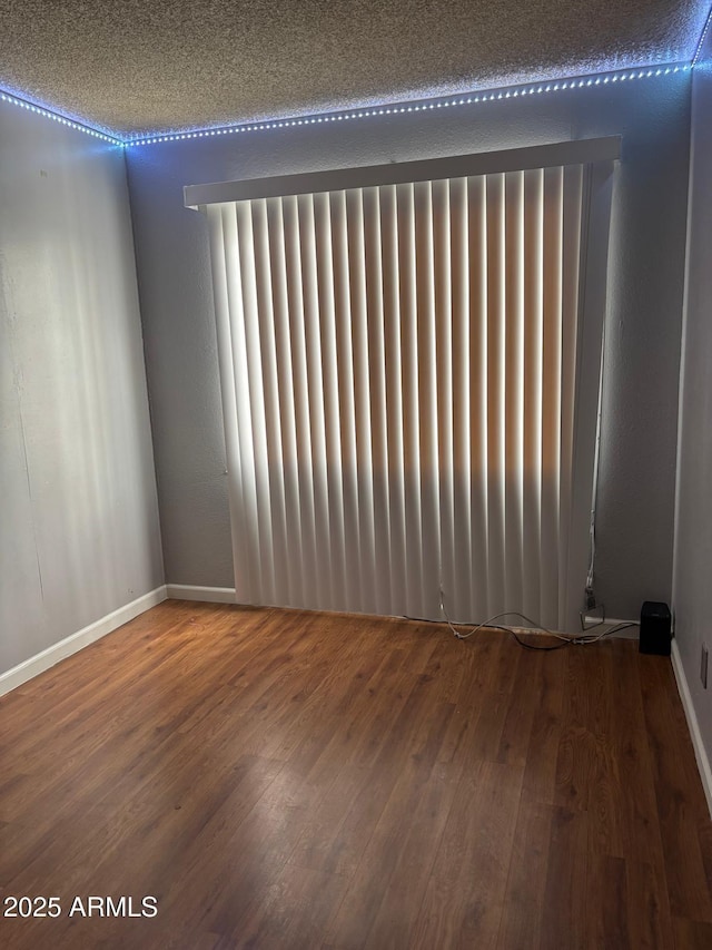 unfurnished room with radiator heating unit, wood finished floors, and baseboards