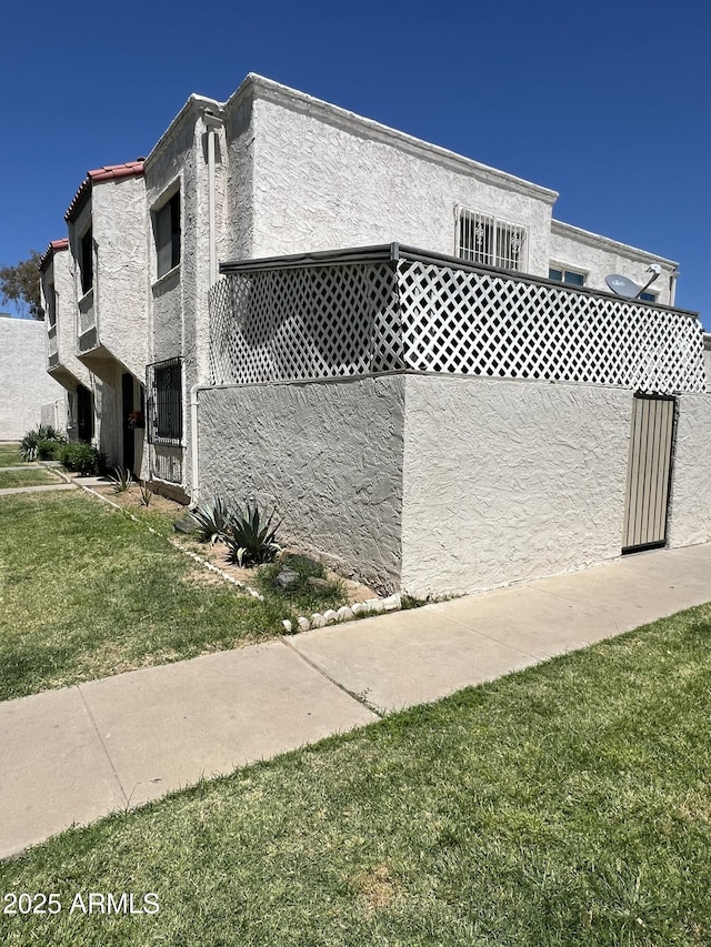 view of side of home featuring stucco siding and a yard