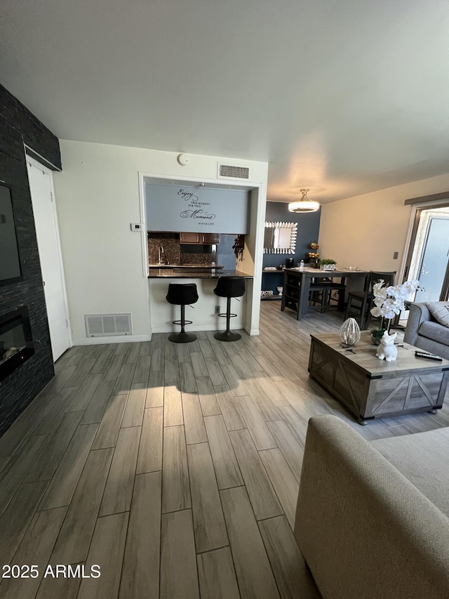 living area with a chandelier, wood finished floors, and a fireplace