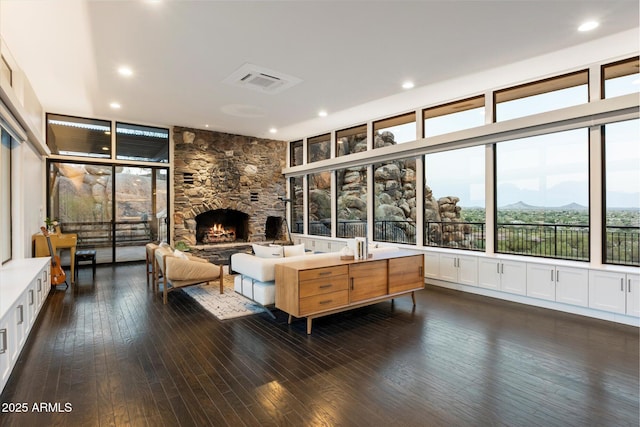 living area featuring recessed lighting, visible vents, a stone fireplace, and hardwood / wood-style flooring