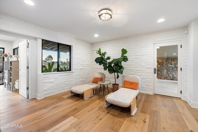 sitting room with light wood finished floors, brick wall, and recessed lighting