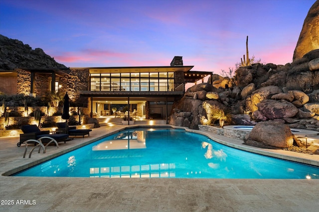 pool at dusk featuring an outdoor pool, a patio area, and a jacuzzi